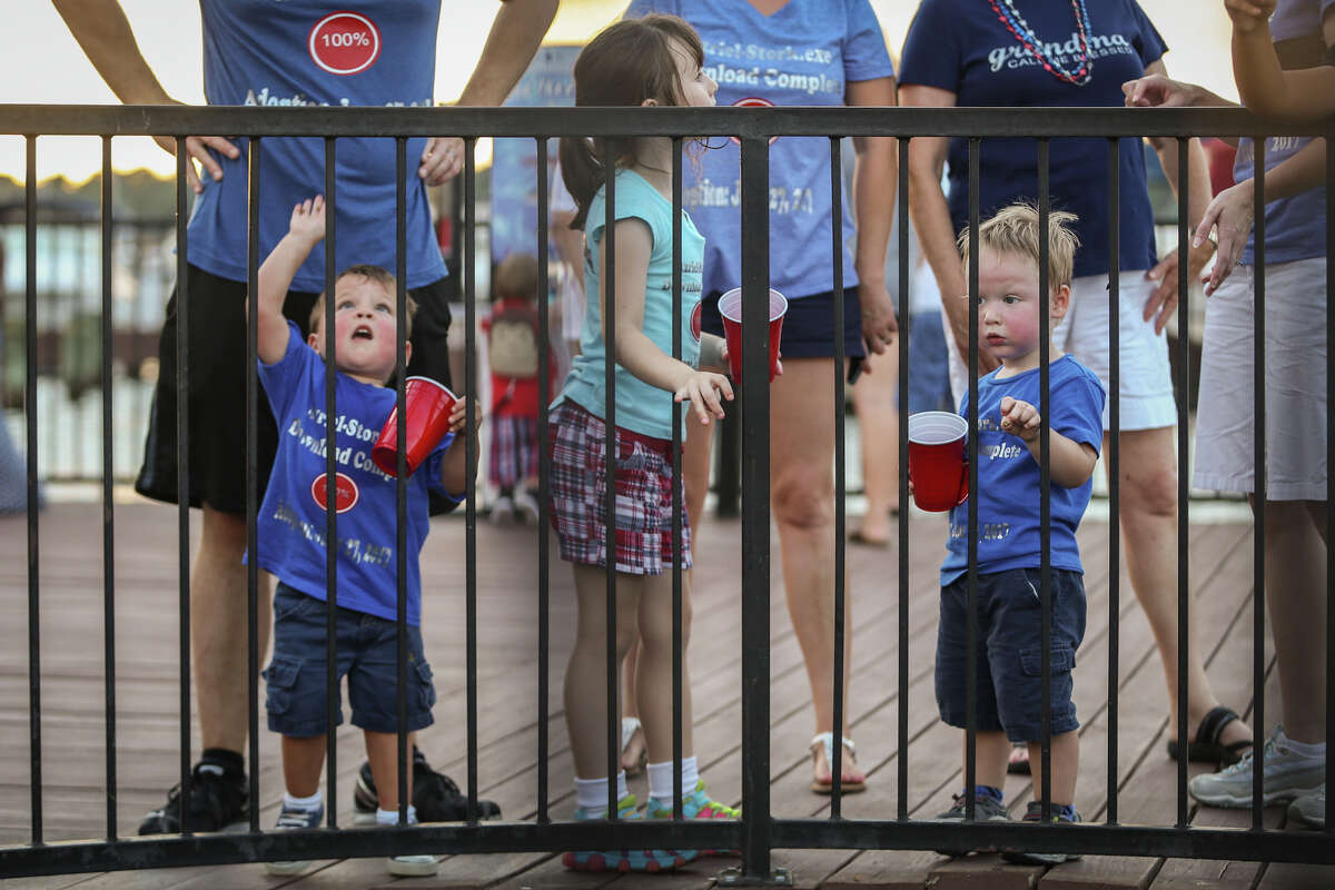 Azriel Stork, 2, Evelyn Welchel, 6, and Isaac Welchel, 2, feed fish at the pier in front of Fajita Jack's before the start of the Fireworks Over Lake Conroe event on Tuesday, July 4, 2017.