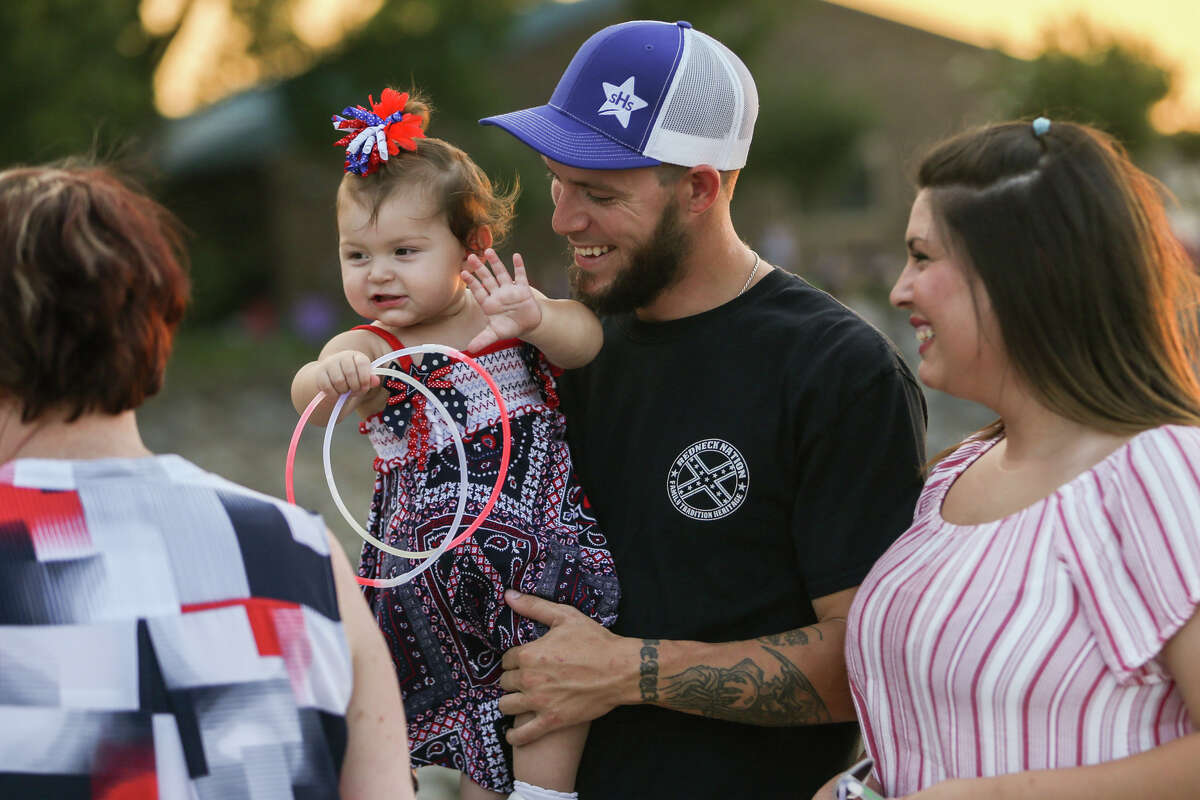 Conroe resident Beaux Leitz, center, holds his 11-month-old daughter Mckenzie as she plays with him and Taylor Anderson, right, during Fireworks Over Lake Conroe on Tuesday, July 4, 2017, on the Lake Conroe Dam.