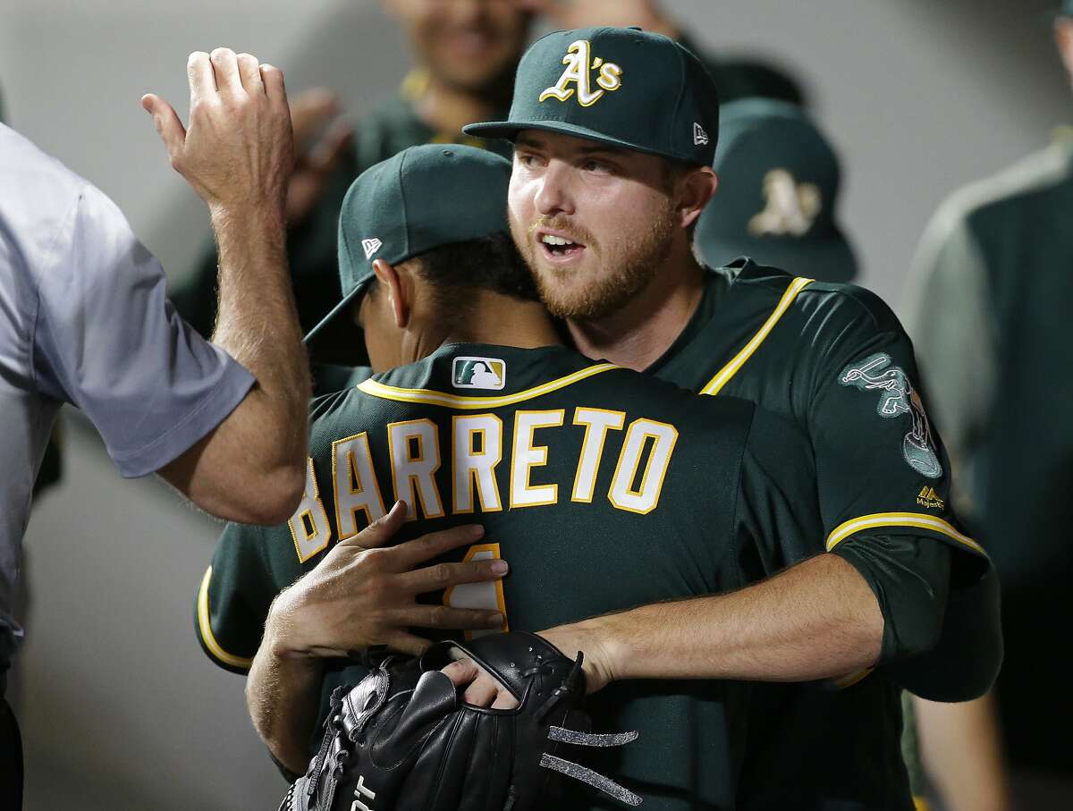 Oakland Athletics starting pitcher Paul Blackburn, right, gets a hug from Franklin Barreto in the dugout after Blackburn was pulled from a baseball game against the Seattle Mariners during the eighth inning, Thursday, July 6, 2017, in Seattle. (AP Photo/Ted S. Warren)