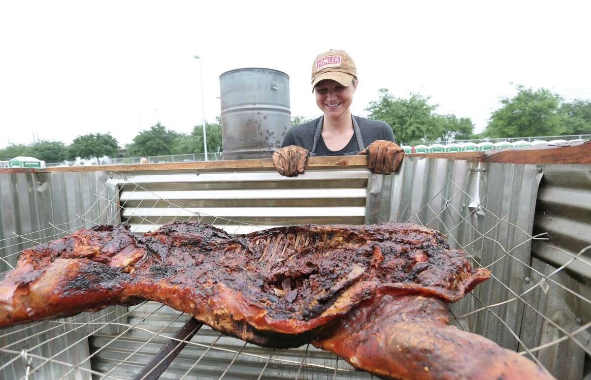 Erin Smith Feges, with Feges BBQ, smiles as she looks at the remaining half of a cooked hog in a homemade oven at the 3rd annual Houston Barbecue Festival Sunday, April 26, 2015, at NRG Park.