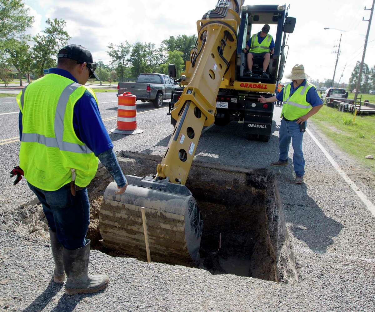 Workers with Montgomery County Precinct 3 dig out a section of road to get to a broken pipe that caused a sinkhole that shutdown one of the east bound lanes on Rayford Road near Wild Rose Drive, Thursday, July 7, 2017, in Spring.