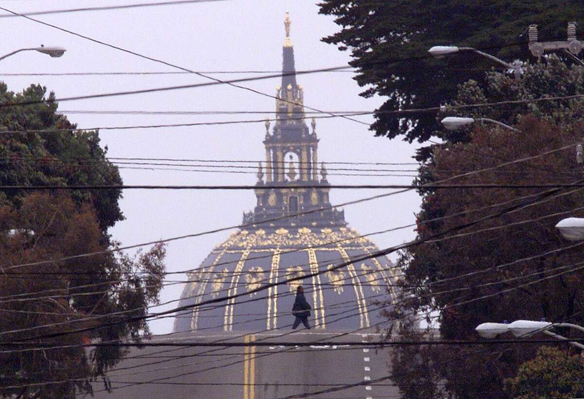 DOME/27MAY99/MN/BW--A woman crosses Fulton Street in San Francisco Thursday while the dome of City Hall looms in the background. It was a gray day on the coast Thursday, but after the fog burned off visibility was descent. City Hall is a good half mile from this pedestrian. By Brant Ward/Chronicle