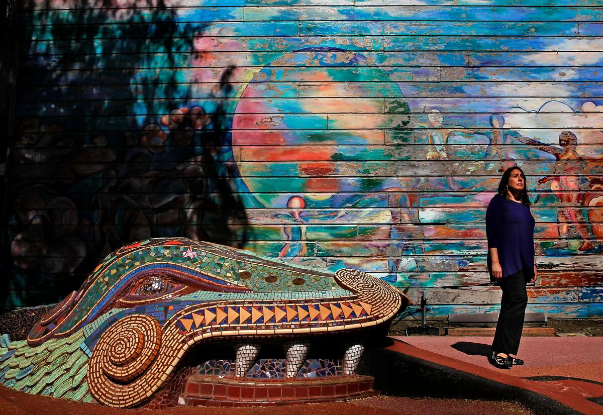 Cory Cordova, at the 24th and York mini park in the Mission neighborhood, in San Francisco, Ca., on Thursday July 6, 2017. She is seen near the mural by�Michael Rios,�Children Dance Around the World, painted in 1982 and repainted in 1990�and the relief sculpture, "The GIfts of Quetzal-Coatl" by Mark Roller, 1982 and one of the many murals that surround the park.