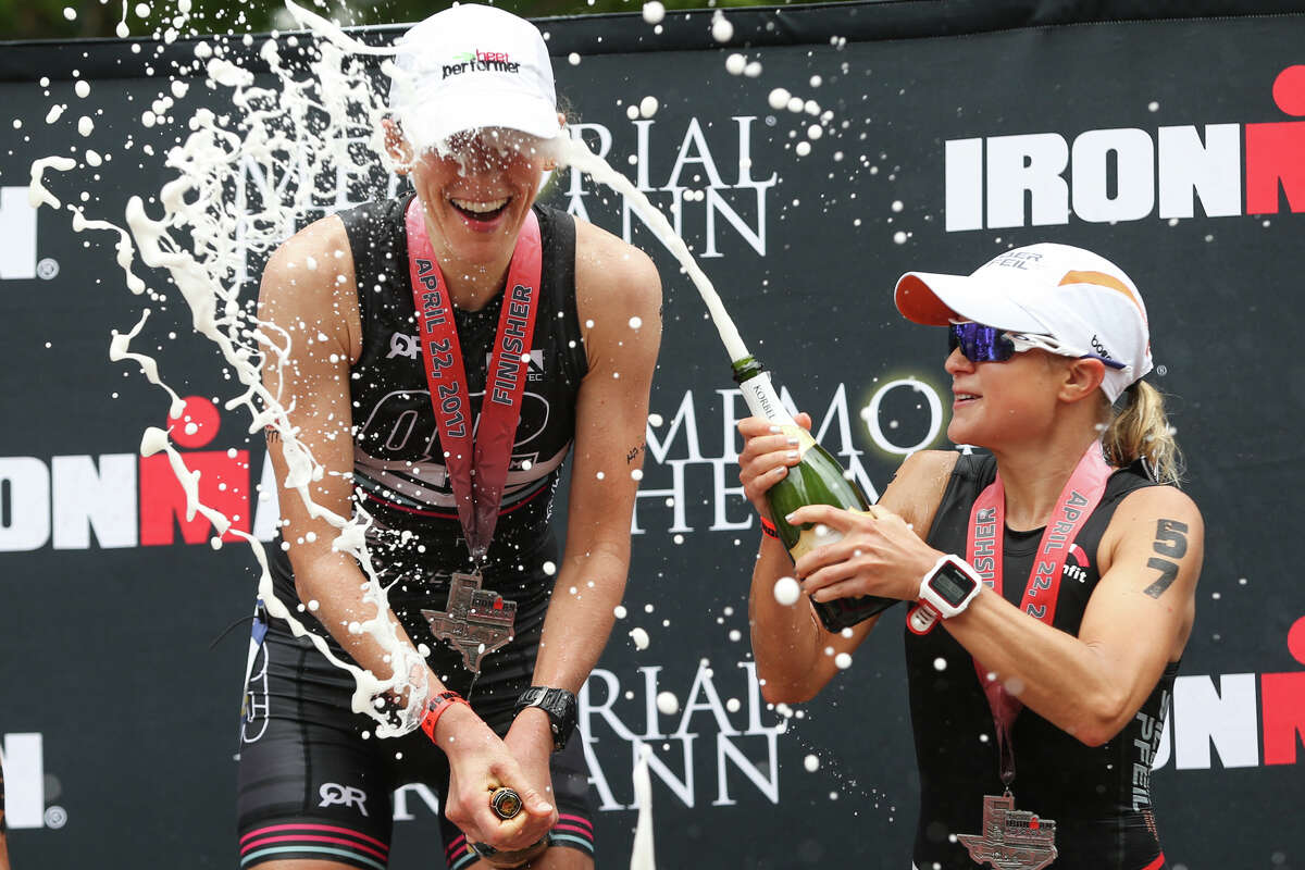 Michaela Herlbauer, of Austria, opens a bottle of champagne in the face of Jodie Robertson, of New York, during the Memorial Hermann IRONMAN North American Championship Texas on Saturday, April 22, 2017, in The Woodlands.