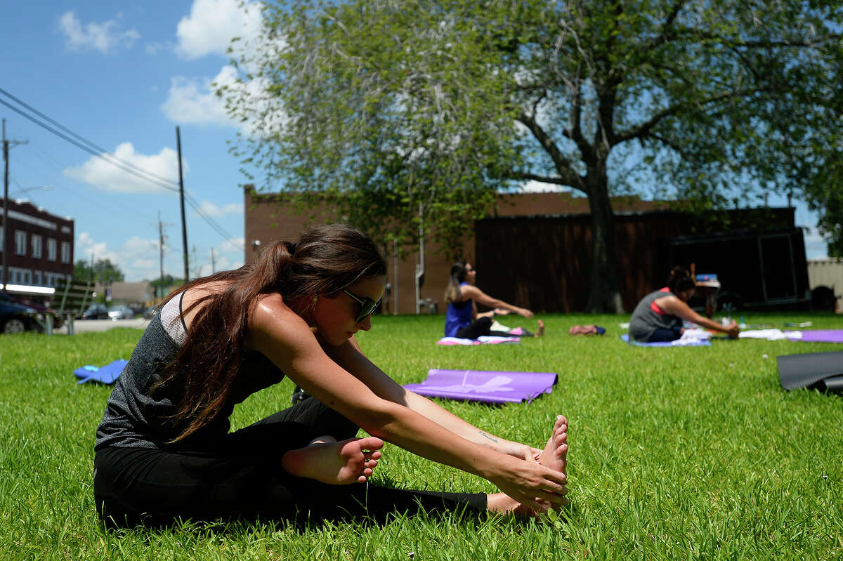 Lauren Rogers stretches during a yoga class at the Neches Brewing Company in Port Neches on Saturday. The brewery hosts the yoga classes once a month in the nearby park. Photo taken Saturday 7/8/17 Ryan Pelham/The Enterprise