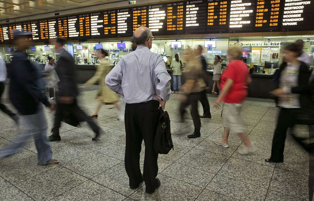 FILE - In this July 15, 2014, file photo, a man consults the Long Island Rail Road departure board amid morning commuters, in New York's Penn Station. Some frustrated Long Island Rail Road riders are suing the Metropolitan Transportation Authority, the LIRR's parent organization, claiming breach of contract, negligence and "intentional infliction of emotional distress," over chronic shutdowns, delays and packed trains. (AP Photo/Richard Drew, File)