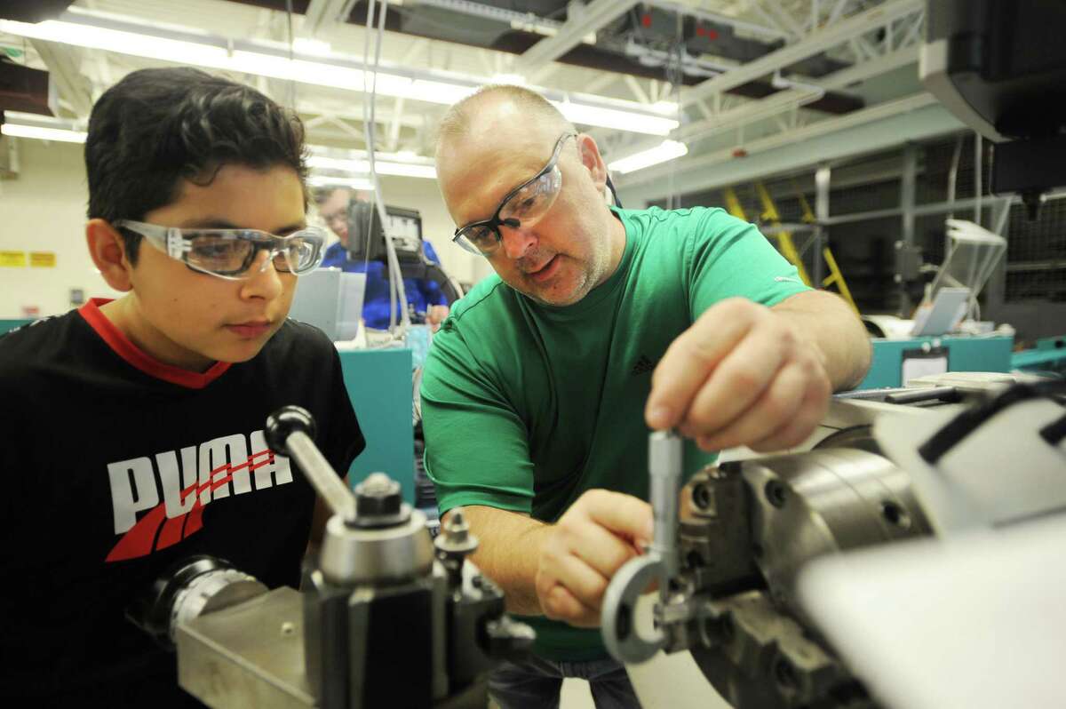 Precision maufacturing teacher Steve Orloski, right, shows Bayron Espinosa, 12, of Ansonia, how to measure thickness with a caliper as he uses an engine lathe in the Young Manufacturers Academy summer program at Emmett O'Brien Technical School in Ansonia, Conn. on Thursday, July 6, 2017.