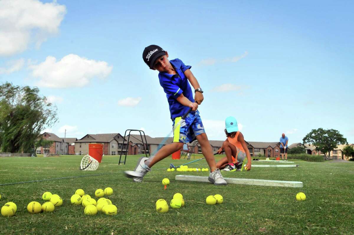 Bryce Huckaby, 7, takes a swing on the driving range while his sister Trinity, 8, places a ball on her tee at Babe Zaharias Golf Course in Port Arthur. (Mike Tobias/The Enterprise)