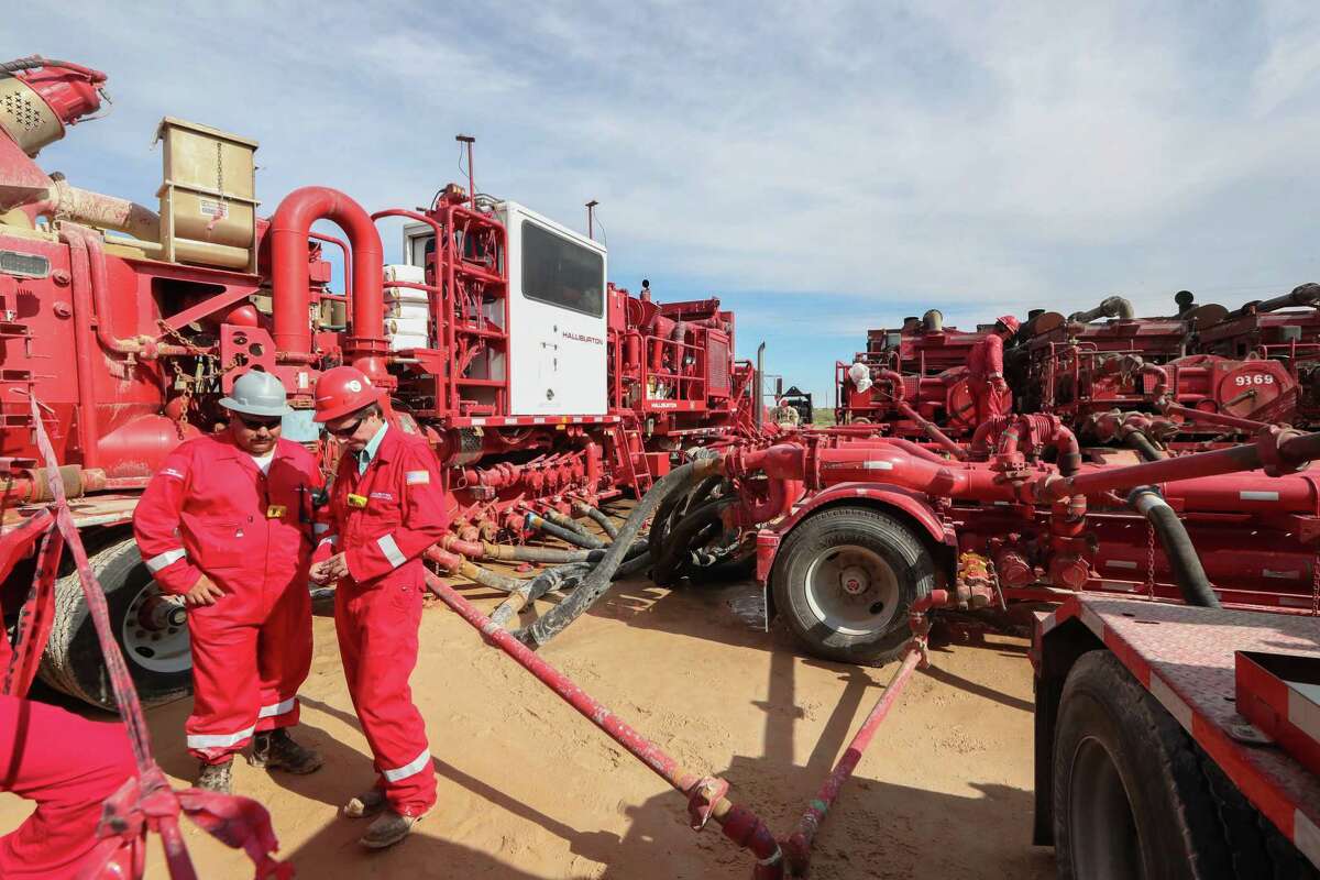 Halliburton employees work near rows of hydraulic fracturing pumping units at a three pad site Monday, June 26, 2017, in Midland.