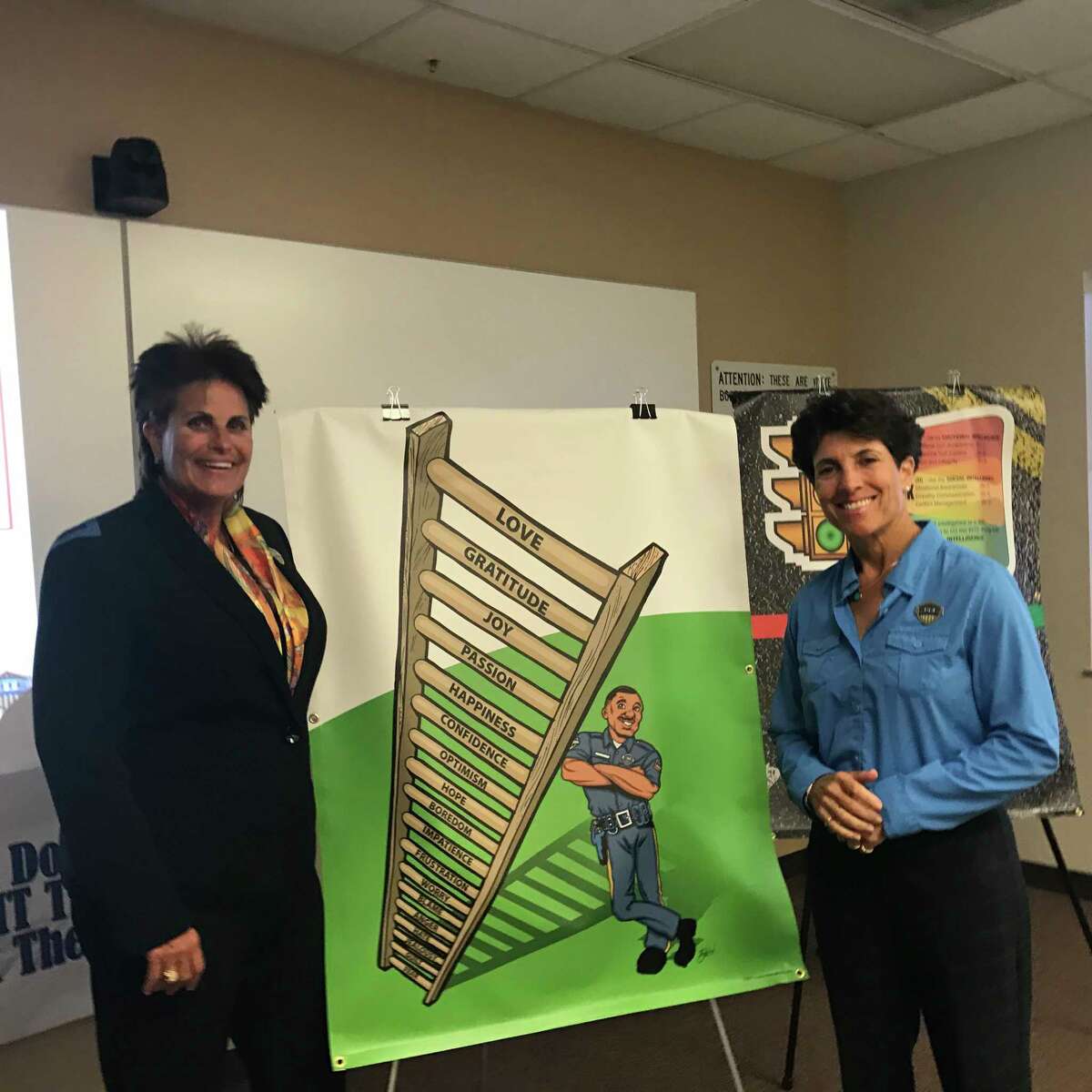 Linda Webb and Randy Friedman, co-founders of Racial Intelligence Training and Engagement Academy, pose by a curriculum poster featuring the 18-tier emotions ladder at a training in Missouri City June 7, 2017.
