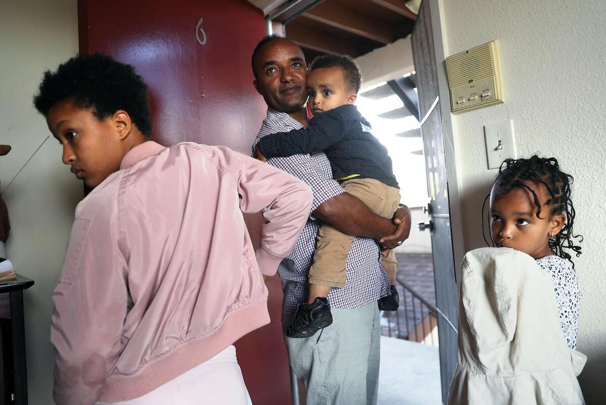 Eritrean refugee Efrem Asefaw Gebregergis, holds his son Yafet , 2, as his daughters, Delina, 12, and Betal, 6, wait to head to the park in Oakland, Calif., on Tuesday, June 27, 2017.