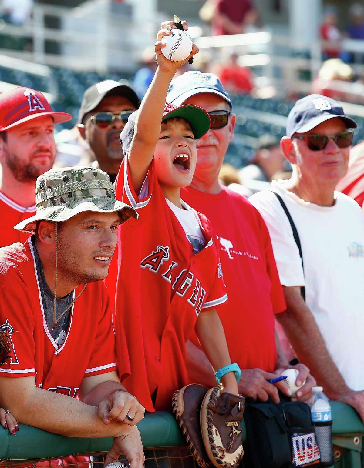 FILE - In this March 8, 2017, file photo, a Los Angeles Angels fan shouts for Mike Trout to sign his baseball, which he did, prior to a spring training baseball game against the Cincinnati Reds, in Goodyear, Ariz. Bryce Harper, Mike Trout and Aaron Judge have become the face of baseball as a gleaming, modernist ballpark and a city known for its Latino culture host the All-Star Game for the first time. (AP Photo/Ross D. Franklin, File)