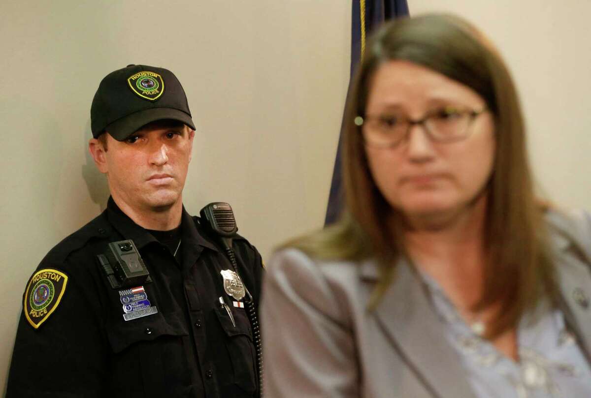 Houston Police officer Chris Meade, left, listens as JoAnne Musick, of the Harris County District Attorney's Office, speaks during a news conference.