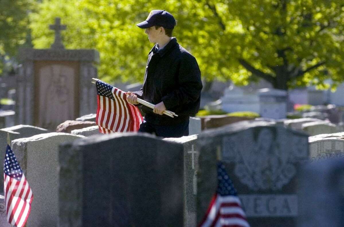 Stamford_051708_ Harrison Martell, of Greenwich and a United States Naval Sea Cadet, helps members of VFW Post 9617 and other volunteers place flags on veterans graves at St. John's Cemetery in preparation for Memorial Day. Kathleen O'Rourke/Staff photo Staff Photo Kathleen O'Rourke