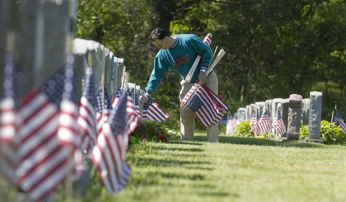 Stamford_051708_ Tony Panaro, of Stamford, helps members of VFW Post 9617 and other volunteers place flags on veterans graves at St. John's Cemetery in preparation for Memorial Day. Kathleen O'Rourke/Staff photo Staff Photo Kathleen O'Rourke