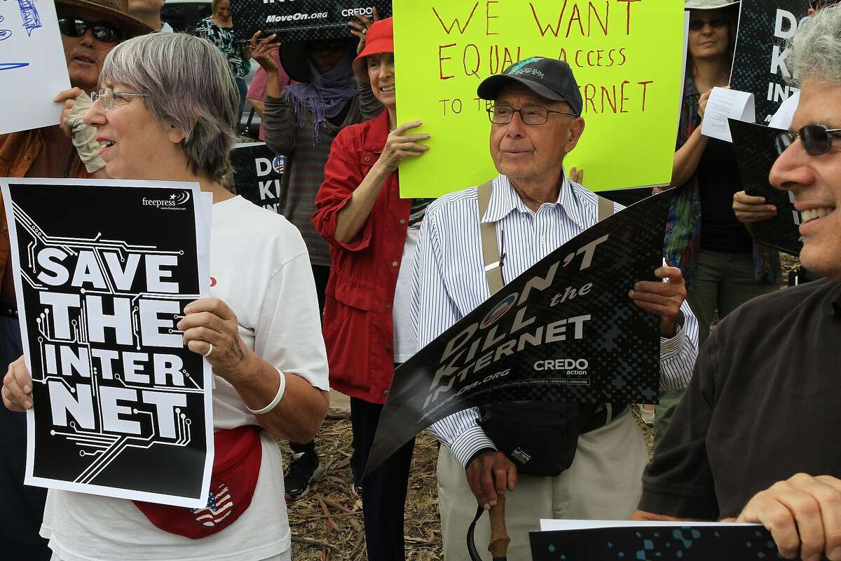 Larry Aronson, center, looks on as protesters chant about net neutrality on Page Mill Rd. on Wednesday, July 23, 2014 in Los Altos, Calif. Protesters interested in net neutrality and conflicts abroad gathered at the corner of Page Mill Rd. and Arastadero to express their concerns.