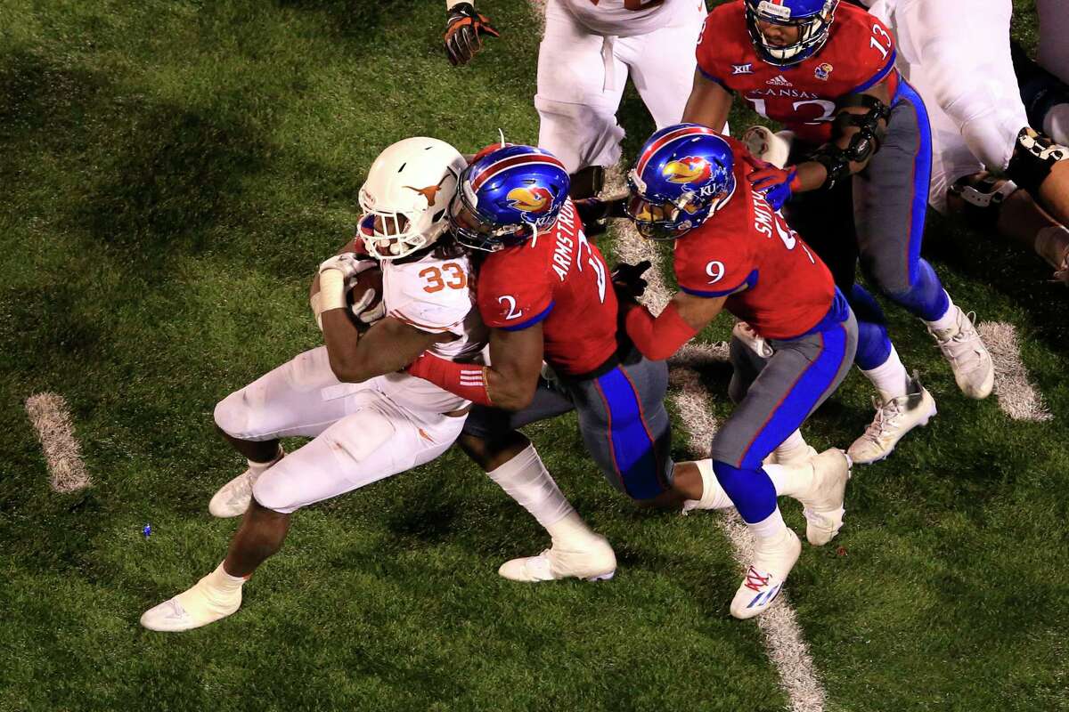 Texas running back D'Onta Foreman (33) is tackled by Kansas defensive end Dorance Armstrong Jr. (2) and safety Fish Smithson (9) during overtime of an NCAA college football game in Lawrence, Kan., Saturday, Nov. 19, 2016. (AP Photo/Orlin Wagner)