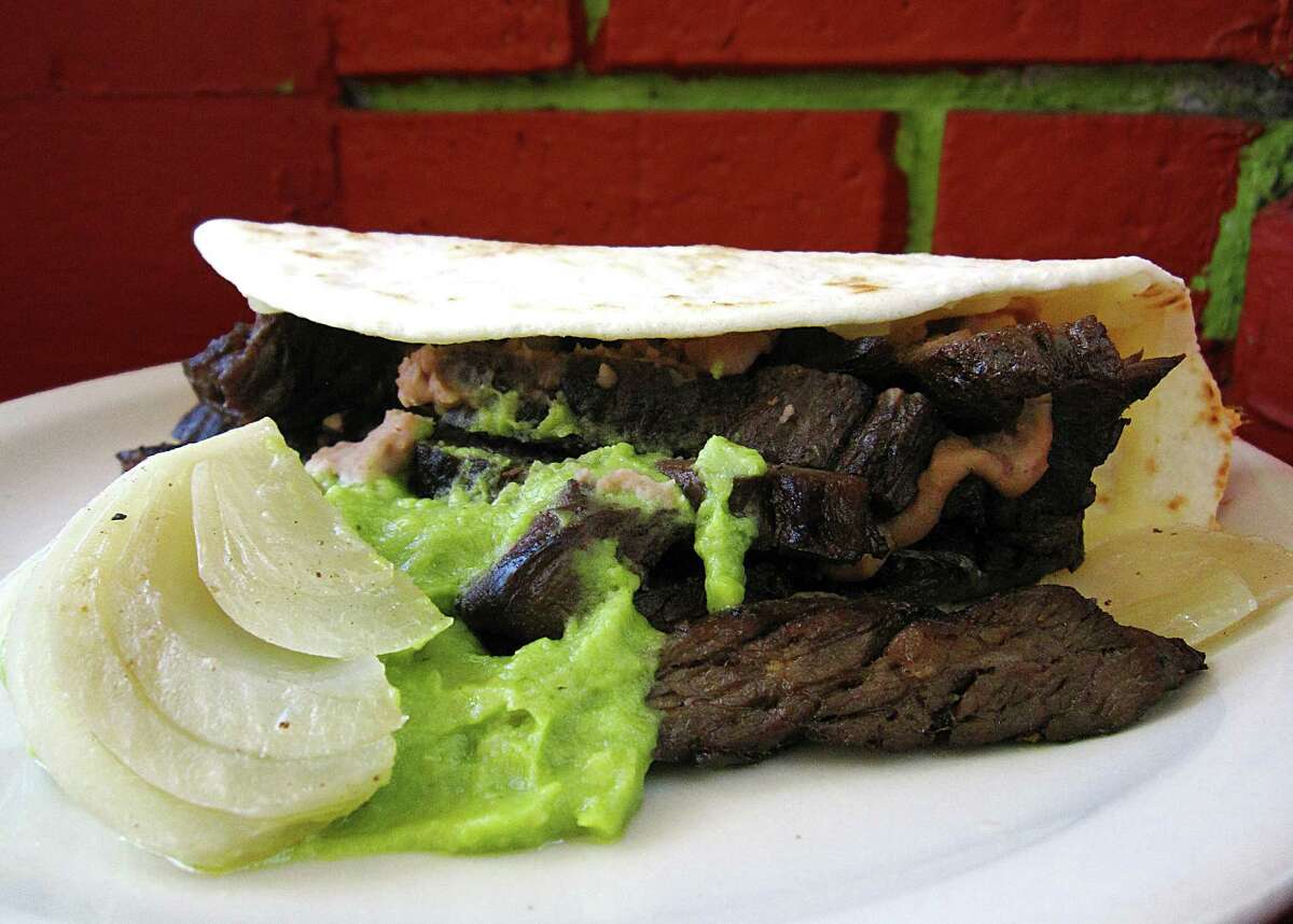 Mini-Norteño taco with beef fajitas, cheese, beans, guacamole and grilled onions on a toasted handmade flour tortilla from Ruthie's Mexican Restaurant.