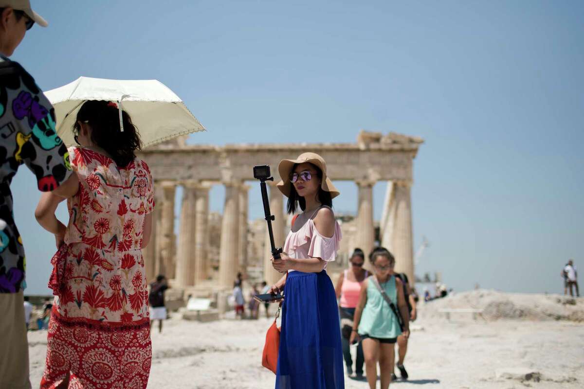 A tourist takes a selfie in front of the fifth century BC Parthenon temple at the Acropolis hill in Athens, Wednesday, July 12, 2017. Greece's Culture Ministry says that all Greek archaeological sites, including Athens' internationally famed Acropolis, will shut during the hottest hours of the day from Wednesday, due to a predicted heat wave. (AP Photo/Petros Giannakouris)