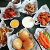 An assortment of wings from Wingstop include (from top left to right): original hot, lemon pepper and mild wings with cheese, ranch, fries, rolls, carrots and celery sticks.