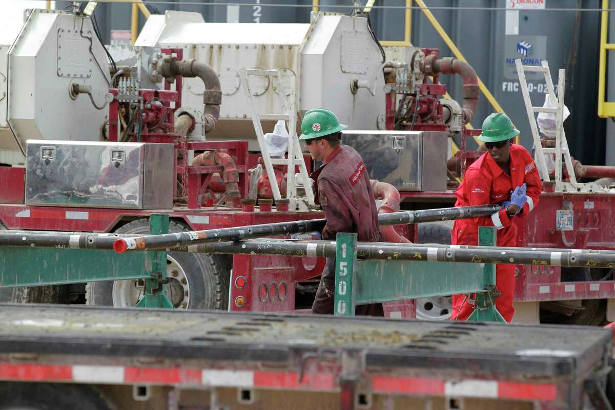 FILE - Halliburton employees move pipe at a three-wellhead hydraulic fracturing site last month in Midland, Texas. The oil giant posted positive gains in its latest fiscal year on July 24, 2017.