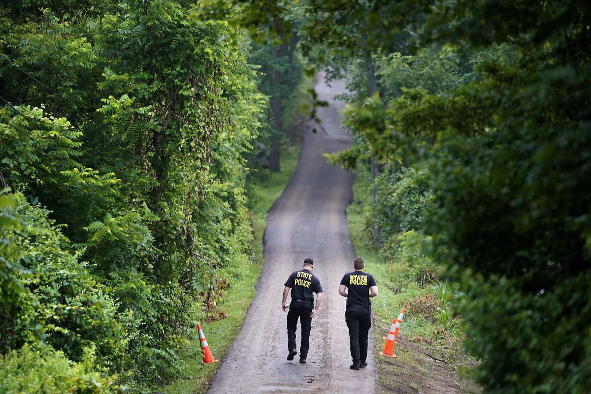 Pennsylvania State Police officers walk up a driveway, Friday, July 14, 2017, in Solebury, Pa., as the investigation of four missing young Pennsylvania men continues. Lawyer Paul Lang, a defense attorney for Cosmo DiNardo, said Thursday that his client has admitted killing the four men who went missing last week and told authorities the location of the bodies. Lang says prosecutors agreed to take the death penalty off the table in return for DiNardo's cooperation. 