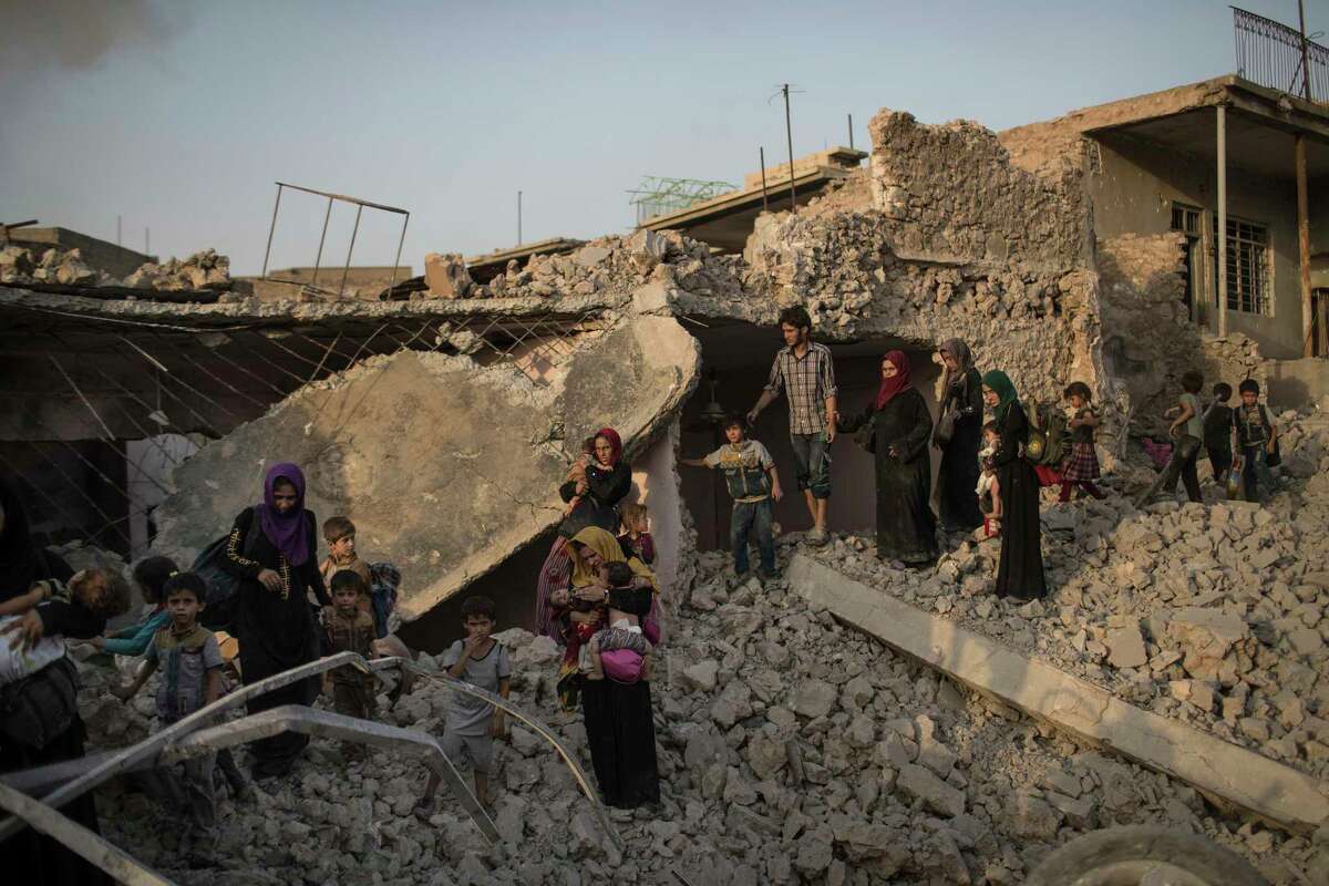 In this July 4, 2017 photo, Iraqi civilians flee fighting between Iraqi forces and Islamic State militants through the rubble of destroyed houses in the Old City of Mosul, Iraq. The population of the city, once numbering 3 million, has been left battered and exhausted, with hundreds of thousands displaced. (AP Photo/Felipe Dana)
