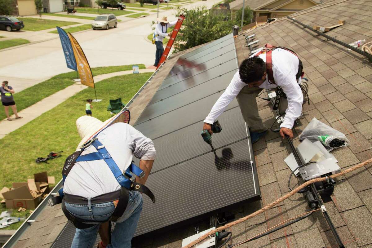 Workers from Alba Solar install panels on a house in Katy. Many solar panels are made in Asia.