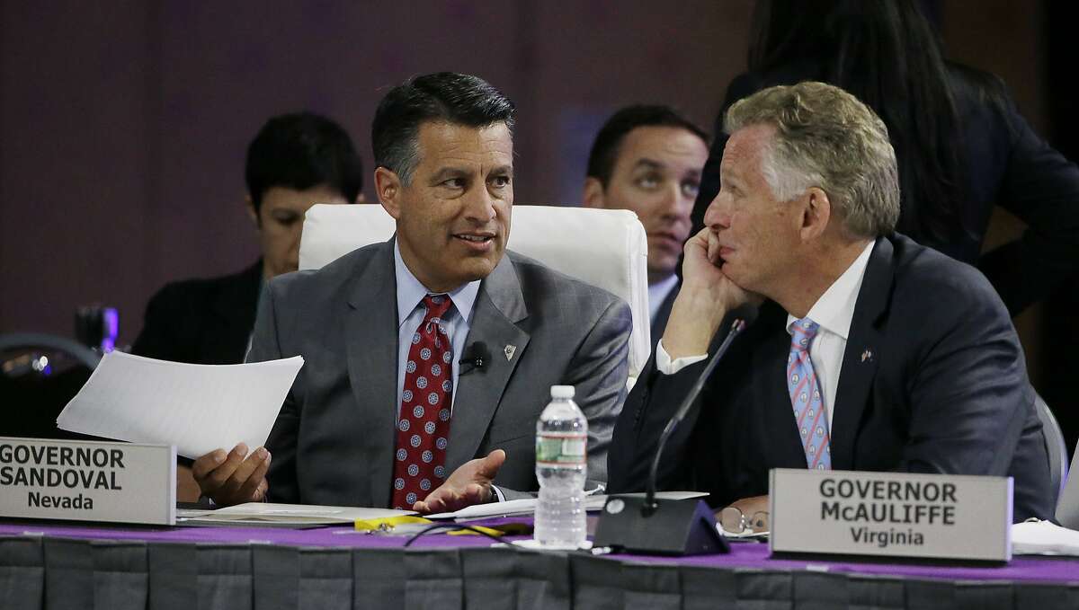 Nevada Republican Gov. Brian Sandoval, left, and Virginia Democratic Gov. Terence McAuliffe converse before Tesla and SpaceX CEO Elon Musk addresses the closing plenary session entitled "Introducing the New Chairs Initiative - Ahead of the Curve" on the third day of the National Governors Association's meeting Saturday, July 15, 2017, in Providence, R.I. (AP Photo/Stephan Savoia)