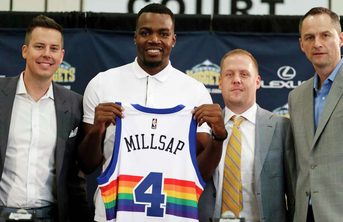 FILE - In this July 13, 2017, file photo, Denver Nuggets new NBA basketball forward Paul Millsap, second from left, holds up his new jersey as Josh Kroenke, team president and governor, left, Tim Connelly, president of basketball operations and Arturas Karnisovas, general manager of the Nuggets, join in for a photograph during Millsap's introduction to the media at a news conference in Denver. The NBA has for years had an issue with the Western Conference being superior to the East, but next season promises to have the widest talent gap yet after a flurry of stars left their teams in the East to try to challenge the mighty Warriors in the West. (AP Photo/David Zalubowski, File)