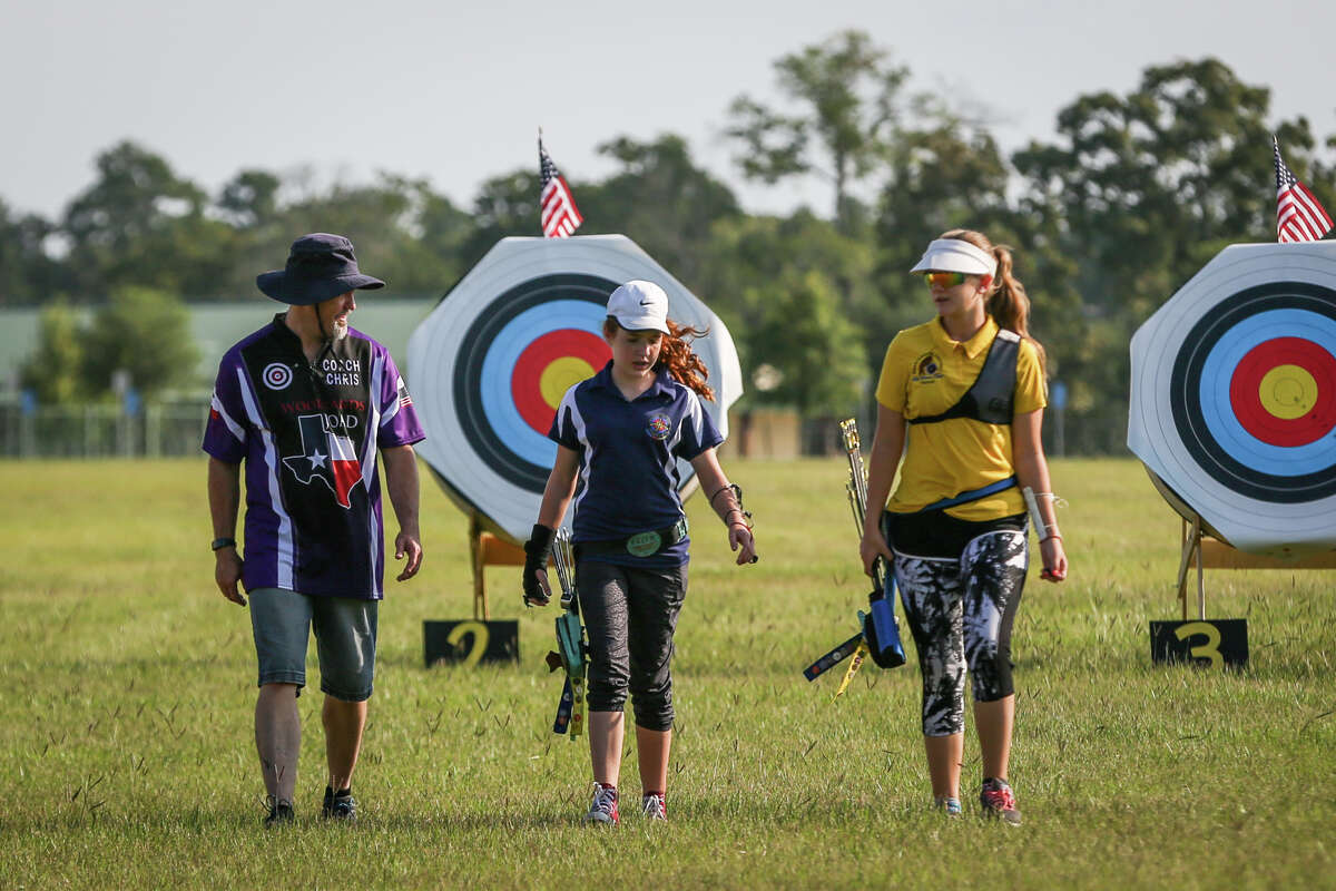 From the left: Chris Meiners, his daughter Jordan, 13, and Grace Cox, 13, walk back from the targets after collecting their arrows during one of the Texas State Archery Association's Texas Outdoor Target Series on Saturday, July 15, 2017, on the fields outside of the Lone Star Convention and Expo Center.