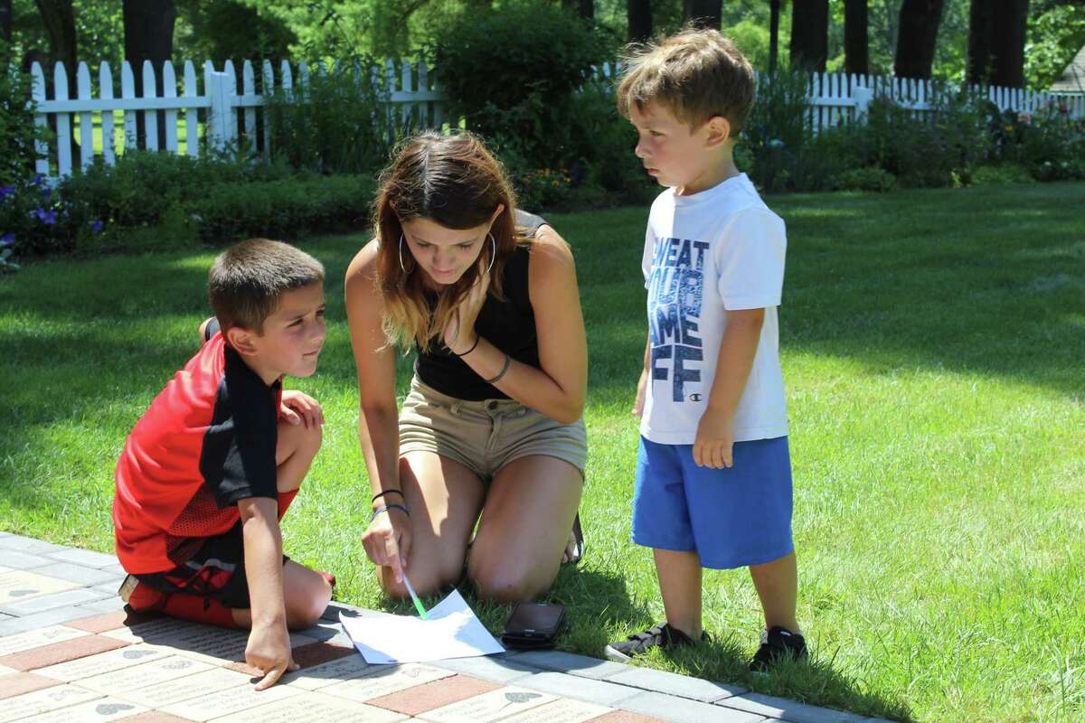 New Milford resident Vanessa Rodgriguez and her sons Julian, 5, left, and Jayden, 3, right, examines the sheet of questions at the Harrybrooke Park scavenger hunt.