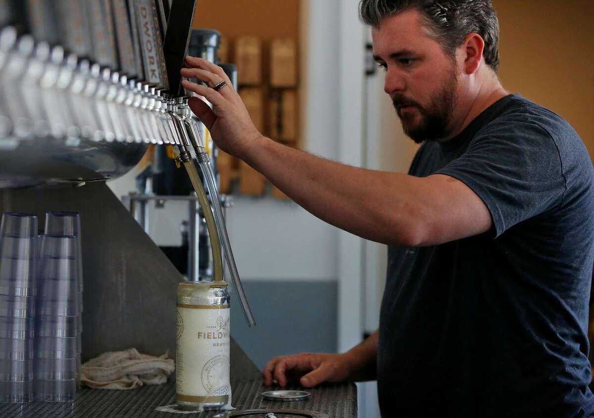 Ryan Murphy, General Manager, fills a growler with beer at Fieldwork Brewing Company July 14, 2017 in San Mateo, Calif.