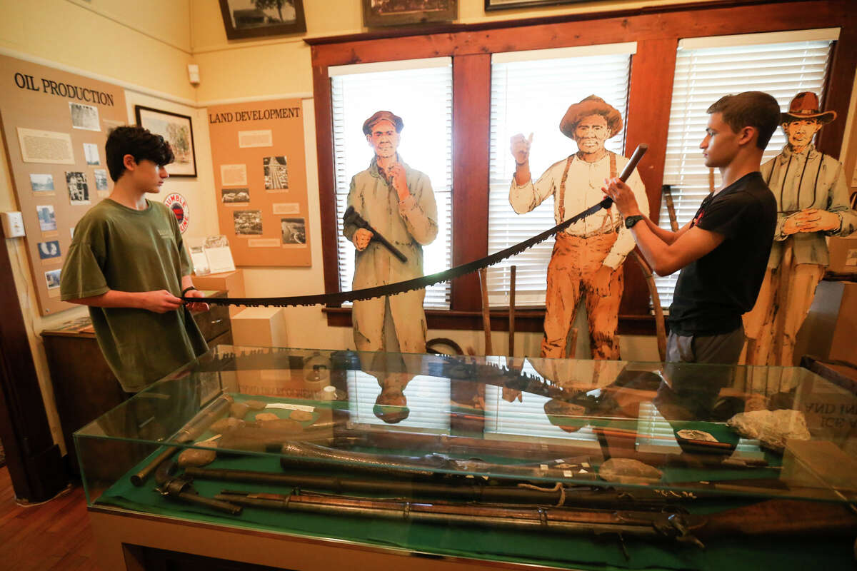 A couple of Boy Scouts hold up a two-man-cross saw, similar to the saw stolen on July 10, at the Heritage Museum of Montgomery County on Tuesday, July 18, 2017.