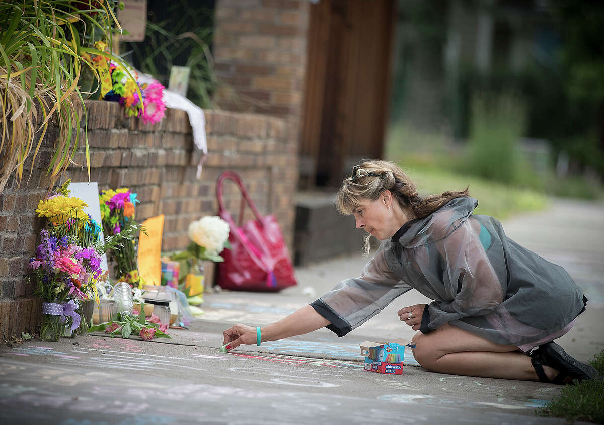 Megan O'Leary, of St. Paul, leaves a message on the sidewalk near the scene where a Minneapolis police officer shot and killed Justine Damond, of Australia, Monday, July 17, 2017, in Minneapolis. Relatives and neighbors of the Australian woman fatally shot by Minneapolis police over the weekend demanded answers Monday about the mysterious shooting in which the meditation teacher was reportedly killed by an officer who fired from the passenger seat of a squad car as the woman stood outside the driver's door. (Elizabeth Flores/Star Tribune via AP)