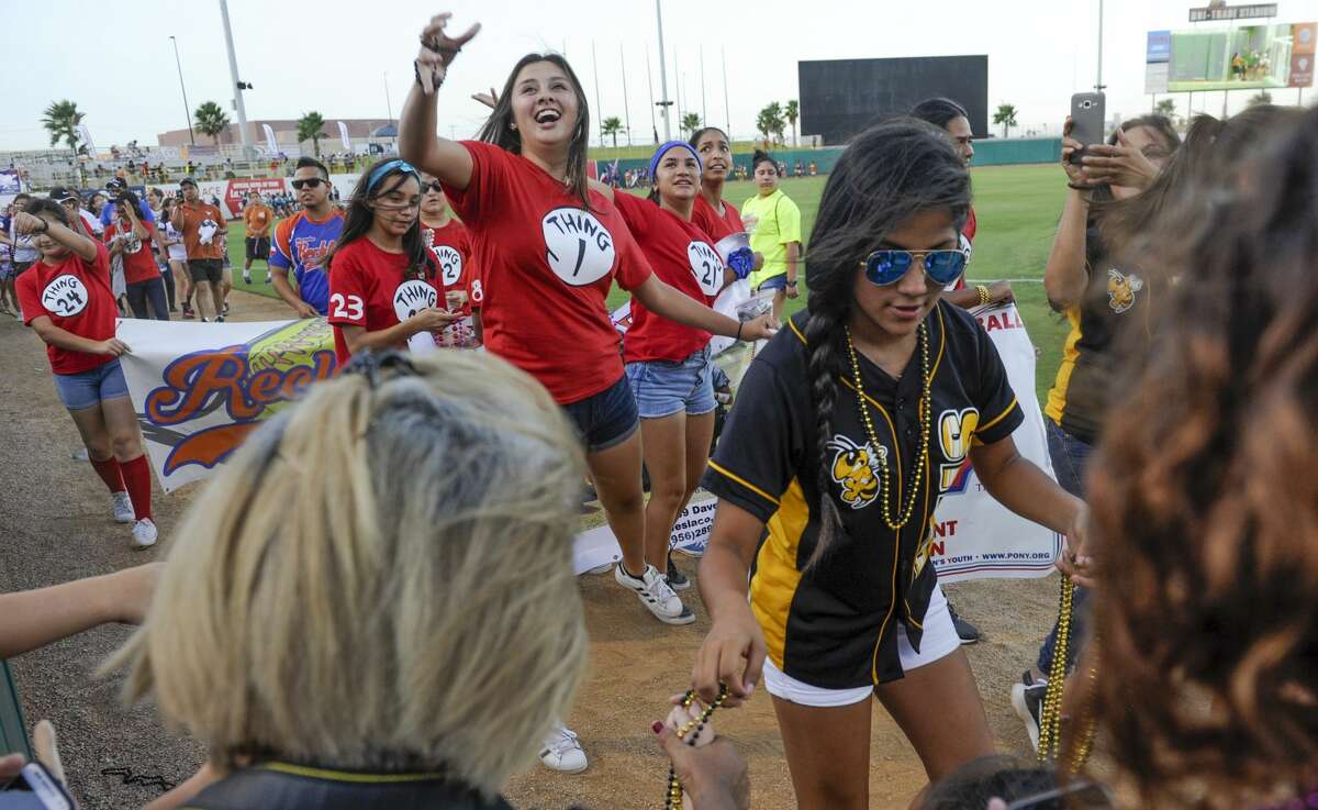 Softball players from across South Texas wave and toss out beads as they take a lap around Uni-Trade Stadium on Tuesday, July 18, 2017 during the opening ceremony of the PONY League Softball World Series.