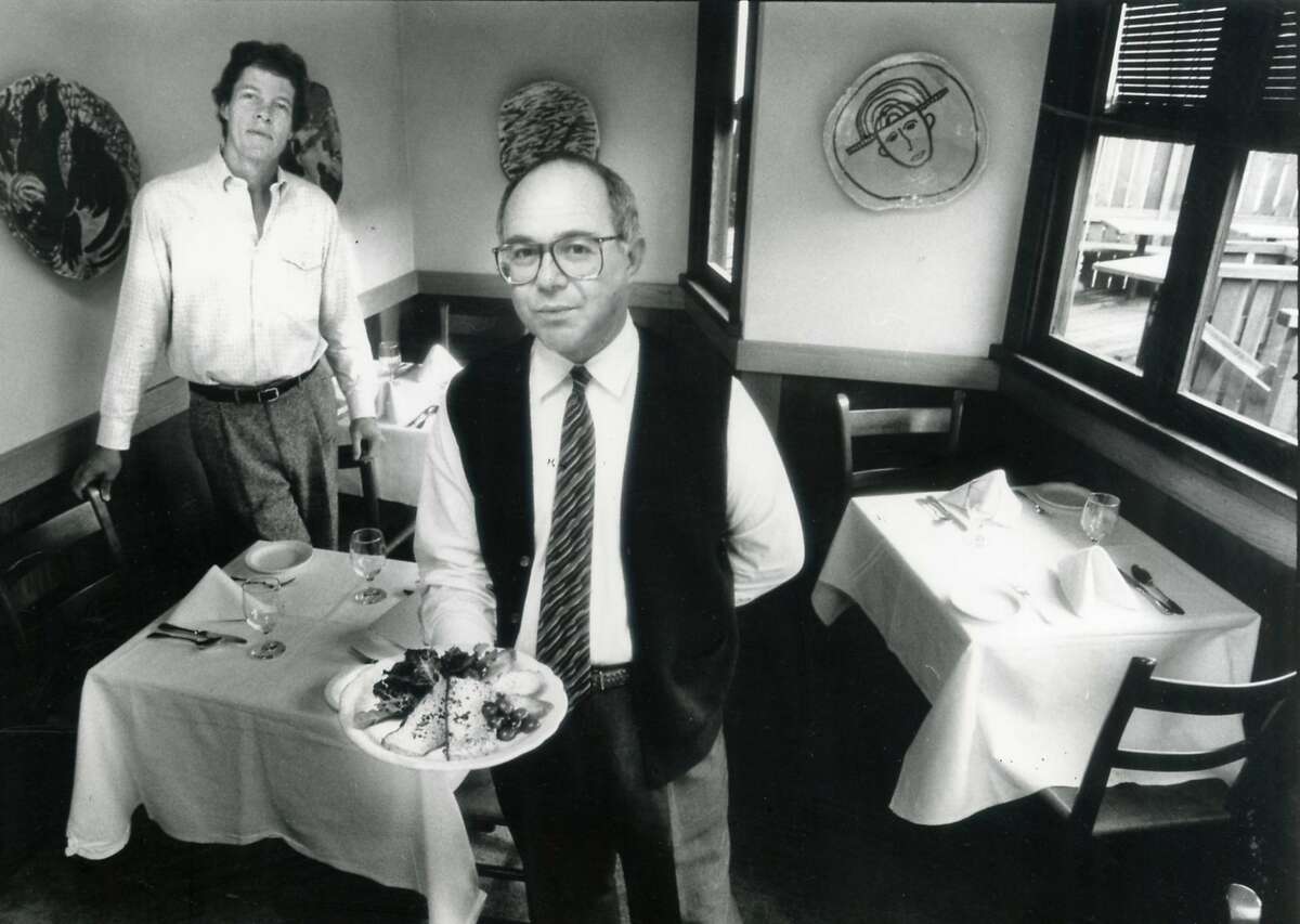 Michael Wild of Bay Wolf in Oakland holds a plate of duck liver flan at his restaurant in 1987. At left is Mark McLeod
