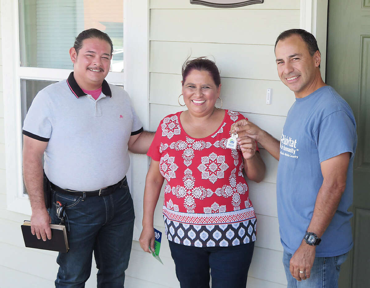 Jose and Maria Lopez smile as Habitat for Humanity-Laredo-Webb County construction manager, Jose "Cuco" Briones, presents them with the keys to their home Wednesday.