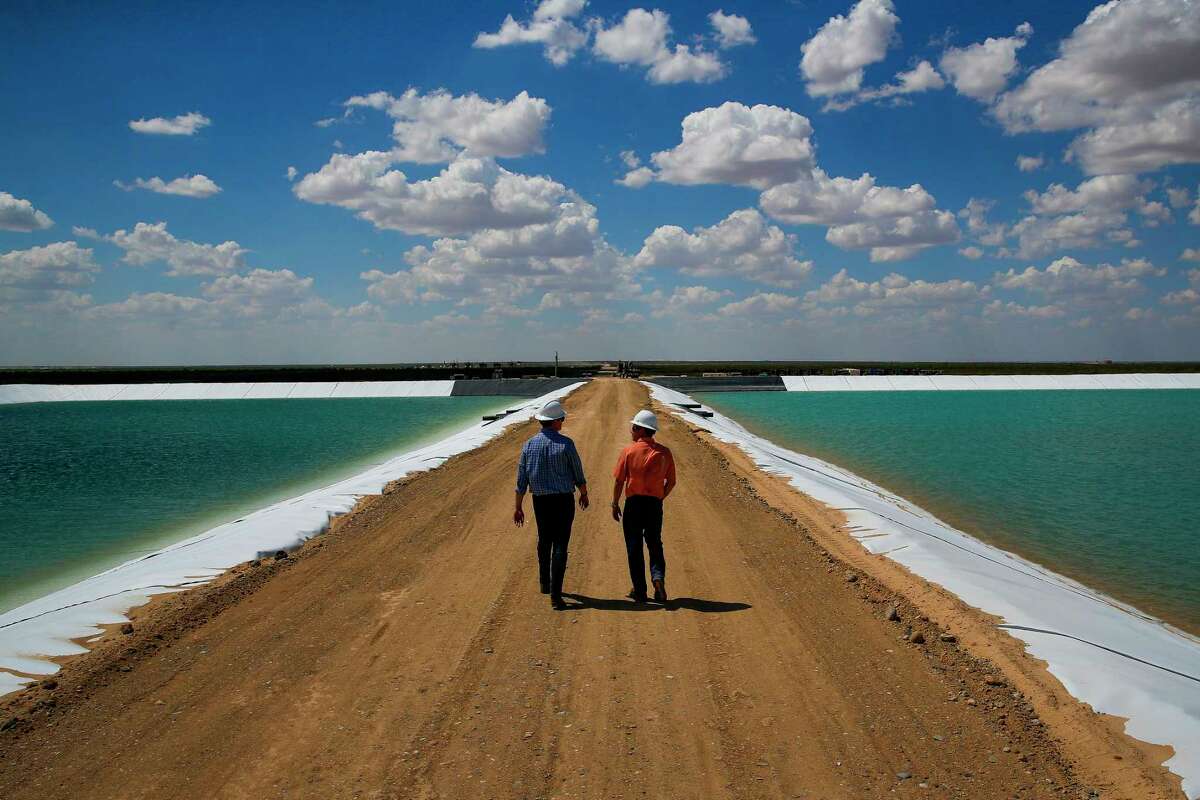 Layne Christensen﻿'s Byron Bevers, left, and ﻿Tim Patrick walk between water retention ponds for the new project in Pecos.﻿