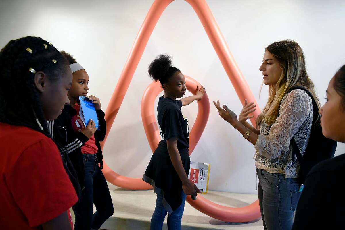 From left, Girls Inc. members Sasha Bonds, Nina Lewis, Jala Williams, and Daniela Jimenez, stand in front of an AirBnB logo statue as they listen to employee Lindsay Bader explain it's meaning during a tour of AirBnB headquarters in San Francisco, CA, on Friday July 7, 2017.