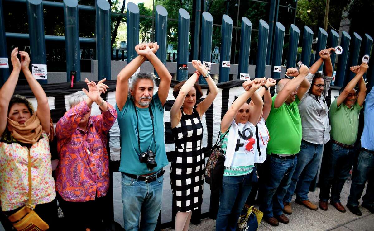 Civil society activists and journalists pretend to turn themselves in during a protest against alleged government spying on the media and human rights defenders, outside the attorney general's office in Mexico City last month. Mexican prosecutors said Wednesday they have opened an investigation into allegations the government spied on leading journalists, human rights activists and anti-corruption campaigners. (Alfredo Estrella/AFP/Getty Images)