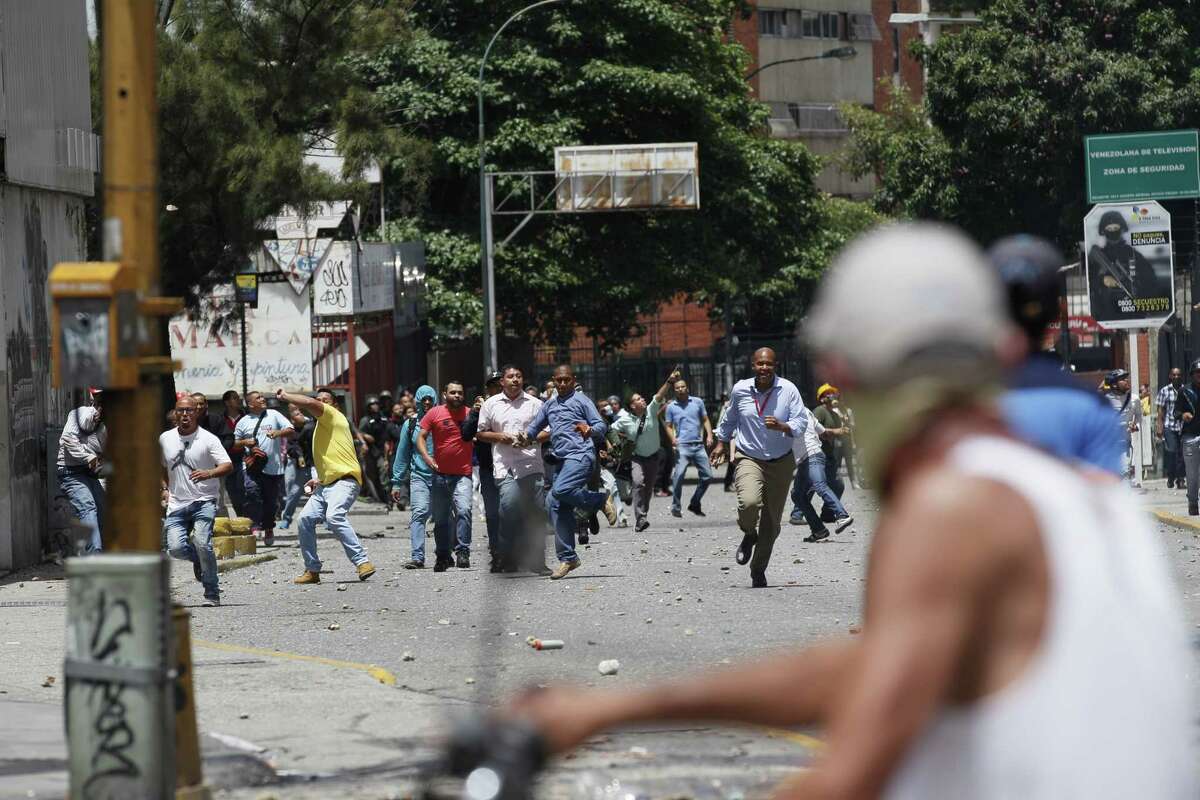 Pro-government supporters confront anti-government protesters in Caracas, Venezuela, Thursday, July 20, 2017. Venezuelan President Nicolas Maduro and his opponents face a crucial showdown Thursday as the country's opposition calls a 24-hour national strike. The country's largest business group, Fedecamaras, has cautiously avoided full endorsement of the strike, but its members have told employees that they won't be punished for coming to work. (AP Photo/Ariana Cubillos)