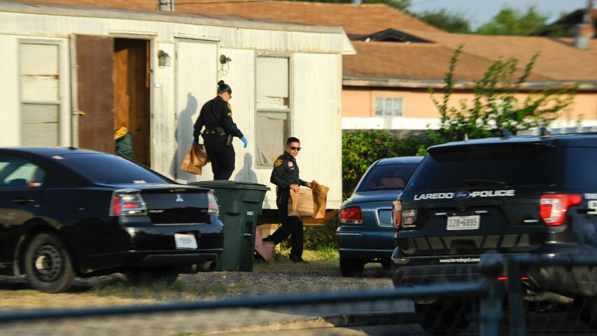 Two Laredo police officers walk out of a suspected stash house with bags of evidence on Thursday.