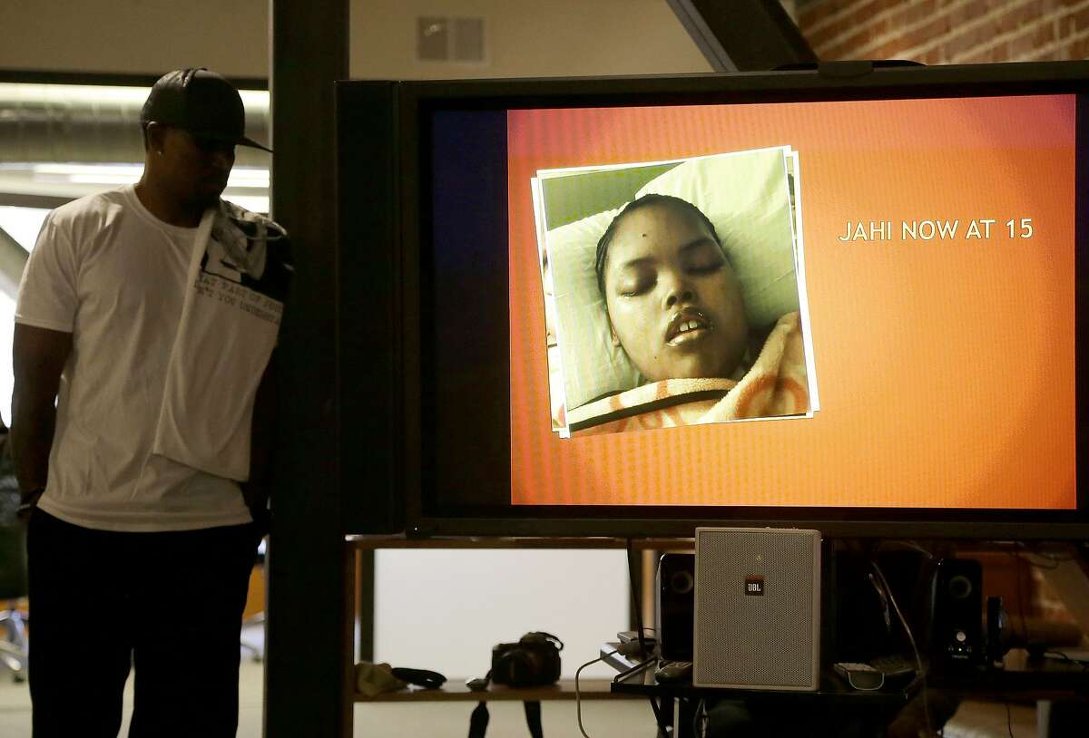 A recent photo of Jahi McMath is shown on a video screen next to her uncle Timothy Whisenton at a news conference in San Francisco, Wednesday, Dec. 23, 2015. McMath's mother Nailah Winkfield's two-year quest to have McMath, who was declared brain dead after complications of a tonsillectomy in 2013, declared legally alive is moving to federal court after attempts to secure an order from a state judge ended in failure. (AP Photo/Jeff Chiu)