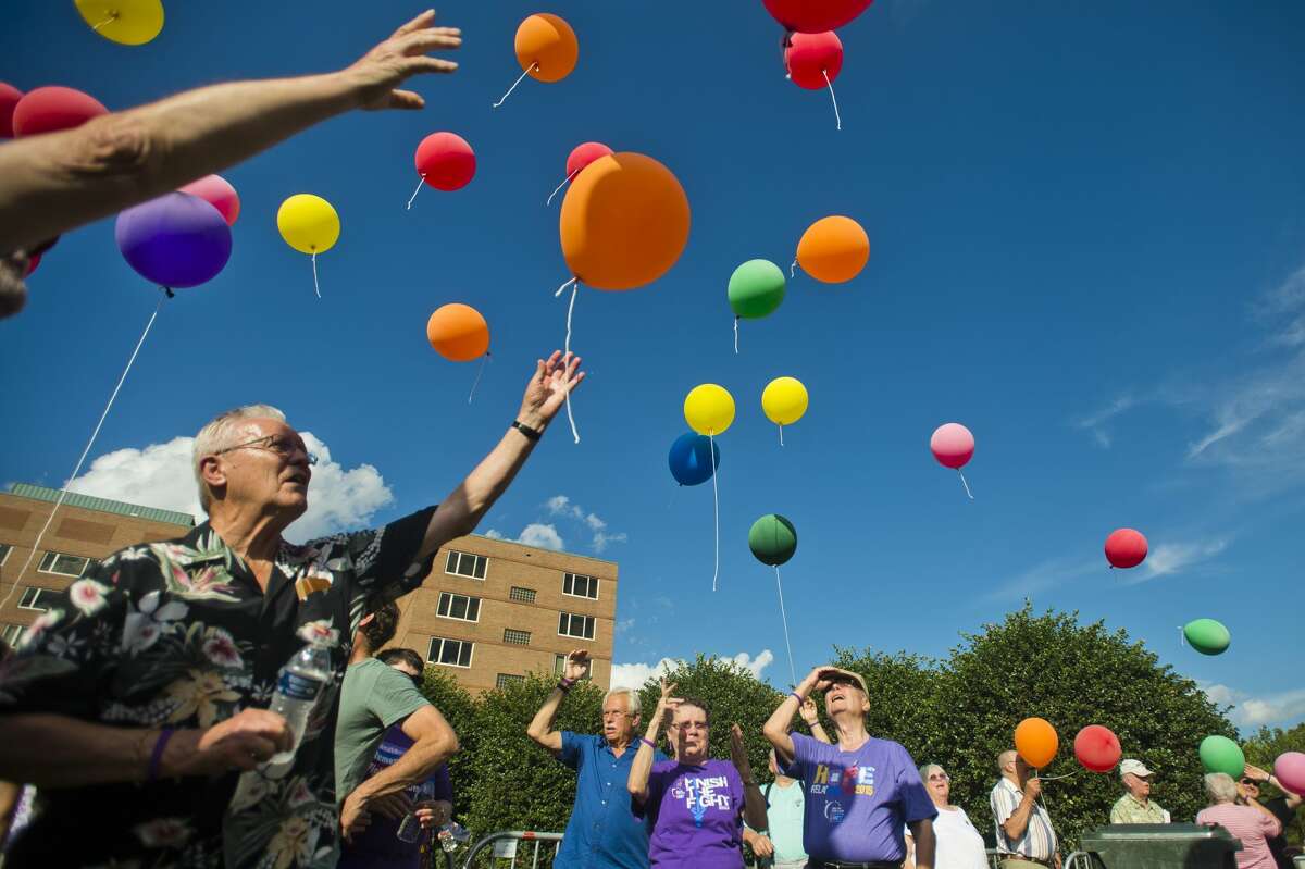 James Peters of Midland, a cancer survivor, left, releases his balloon along with dozens of others during the annual Cancer Services of Midland balloon release on Thursday near The H Hotel.