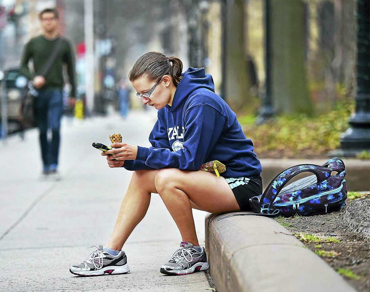 (Catherine Avalone - New Haven Register) New Jersey resident Tori Campbell, a senior at Yale University majoring in english and educational studies, sits on Chapel Street in New Haven, enjoying an ice cream, Thursday, March 10, 2016. Campbell said, "I went out for a run and decided to keep shorts on all day. I love spring in New Haven, it even smells like spring today."