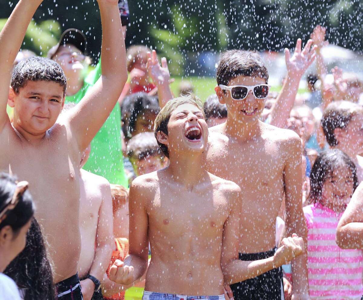 Boys and Girls Club of Greenwich camper Michael Perrone, 12, center, along with other campers including Austin Baabdaty, 12, left, get blasted with water from a fire hose during the annual Christmas in July event at Camp Simmons, Greenwich, Conn., Friday afternoon, July 21, 2017. The event has been taking place for almost two decades and courtesy of the Greenwich Fire Department, Santa arrives on a Greenwich fire truck, tosses candy canes to campers and then cools them down with water from a fire hose.