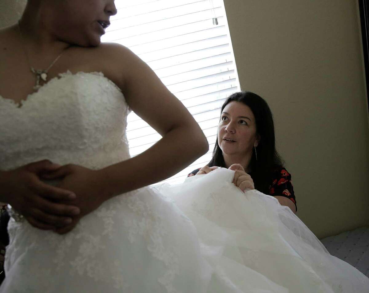 Monica Narvaez helps Marcela Trejo of Houston with her wedding dress. Narvaez took 30-plus dresses from Alfred Angelo's three Houston stores before they shut down with a day's notice.