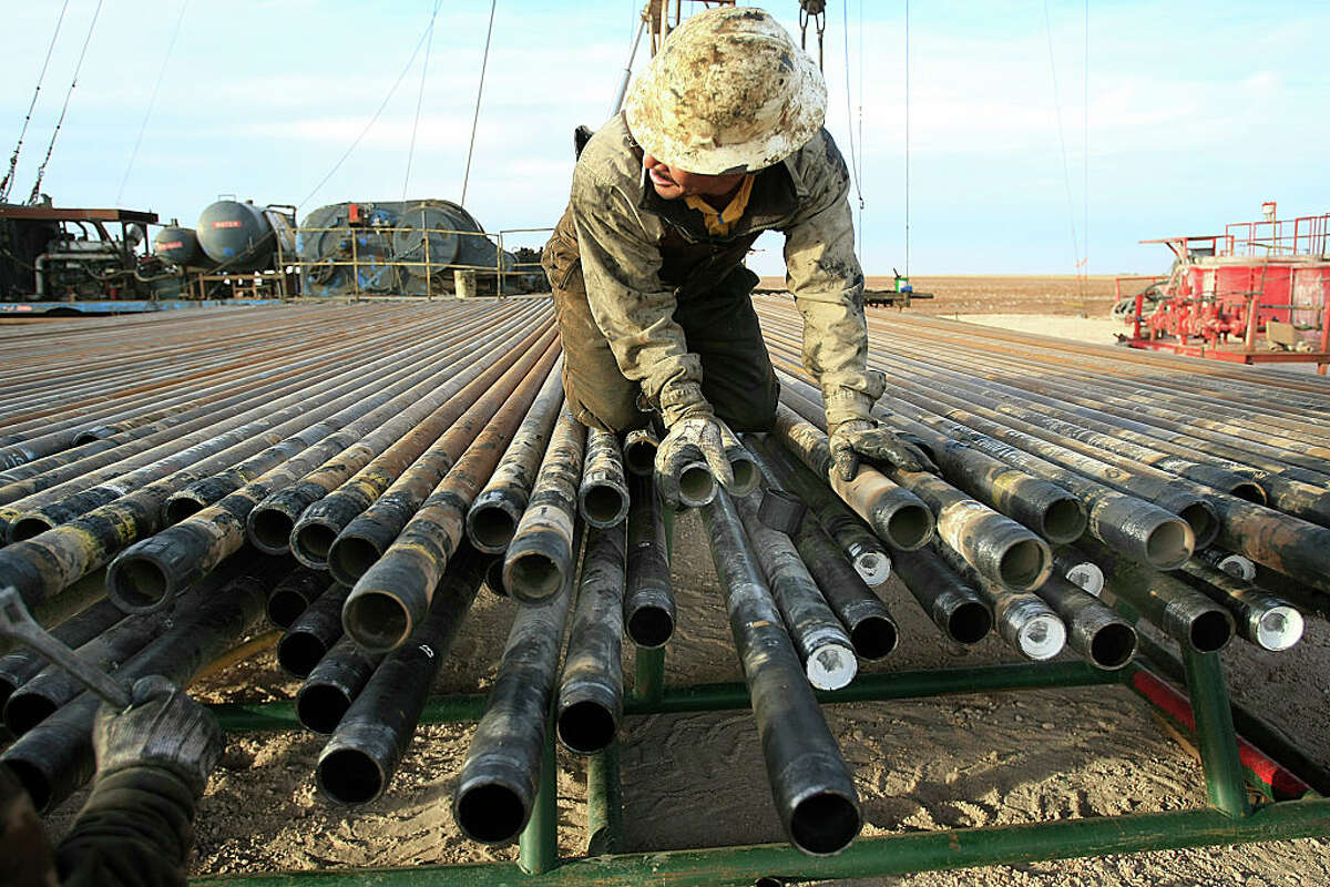 ﻿An oil rigger prepares pipes at a Schlumberger field in Midland. ﻿The company says its onshore North American revenues jumped 42 percent from the first quarter.