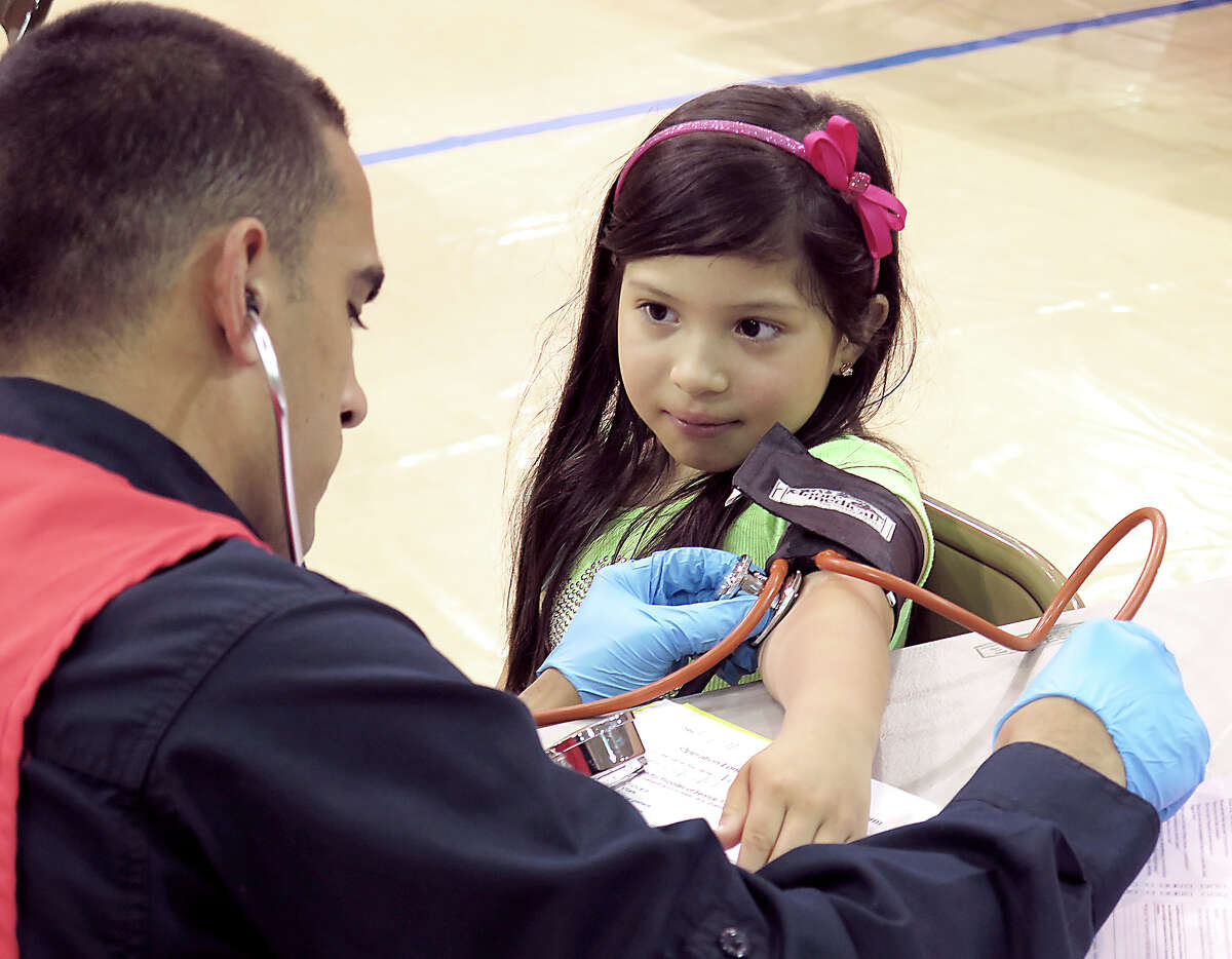 Dyanna Ventura, 6, has her blood pressure taken by Laredo Fire Department Cadet Roger Rueweler Monday morning at the Alexander High School gym where Operation Lone Star is taking place.
